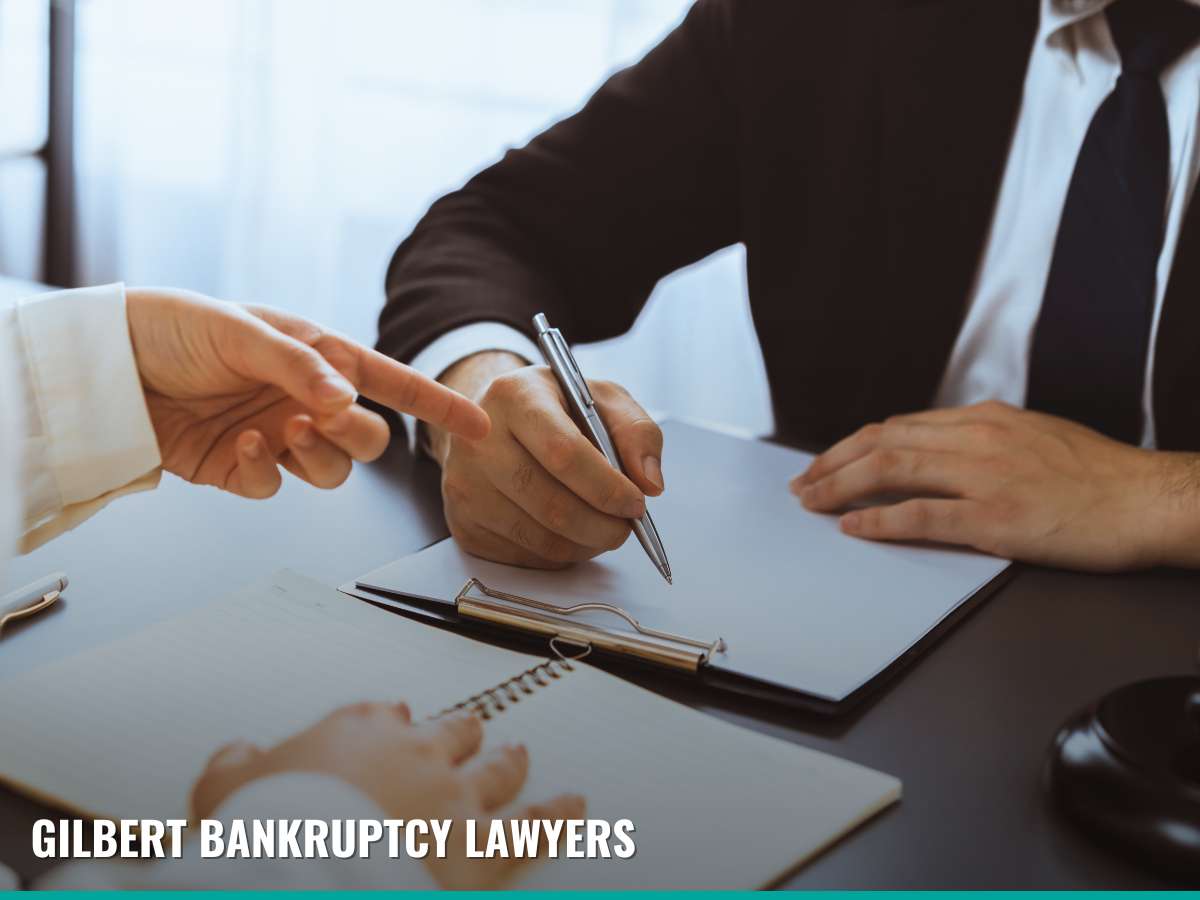 Close-up of a gavel on a table with two professionals discussing in the background, representing Gilbert Bankruptcy Lawyers specializing in bankruptcy exemptions